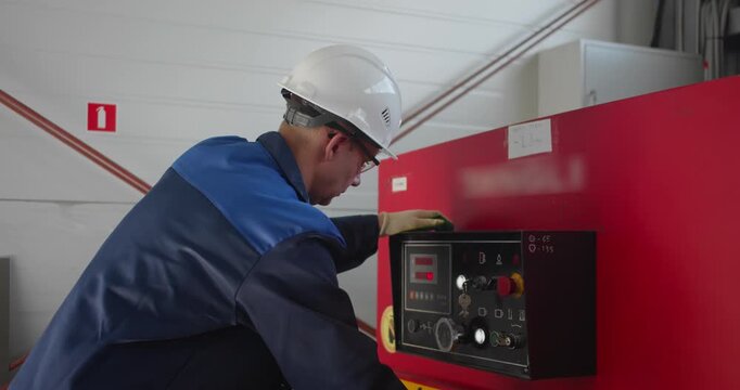 Factory worker operating guillotine shear machine for cutting metal sheets. Industrial production scene focused on blue-collar manufacturing jobs