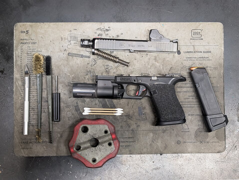January 27, 2026. Baltic States &mdash; High-angle view of a disassembled Glock 19 Gen5 pistol on a technical cleaning mat with professional tools for maintenance and upgrade in a workshop.