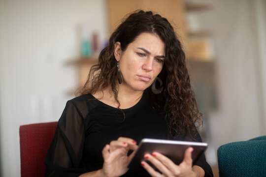 Portrait of a Confused woman sitting on a couch using a digital tablet
