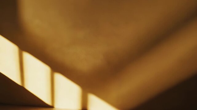 Warm sunlight through a window forms geometric shadows on textured wall and smooth floor, creating abstract patterns and a calm, minimalist interior with golden morning glow