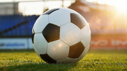 Fototapeta premium Low angle shot of a football on grass with sun flare, concept of sports motivation and victory