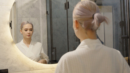 Woman looking in the mirror and touching her hair