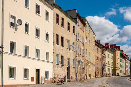 The historic streetscape of Zgorzelec, Poland, a winding cobblestone street lined with historic multi-story residential buildings. 