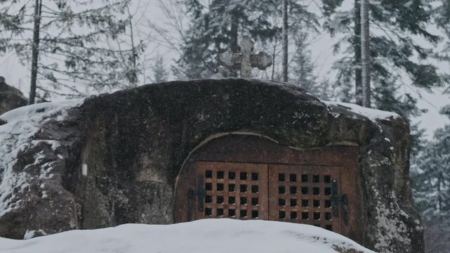 Snow Covered Stone Cave With Gate, Weathered Rock Shelter Carved Into Boulder, Wooden Lattice Door Framed By Moss And Icicles,