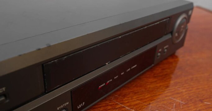 Manual insertion of VHS tape into video player. Physical media and retro video workflow