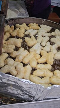 Golden Fried Delights: Close-up of deep-fried dough sticks floating in hot oil, a common culinary delight.