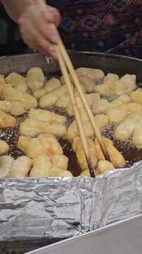 Golden Fried Delights: Capturing the art of street food, delicious, golden fried dough sticks sizzle in a pan, a culinary masterpiece. 