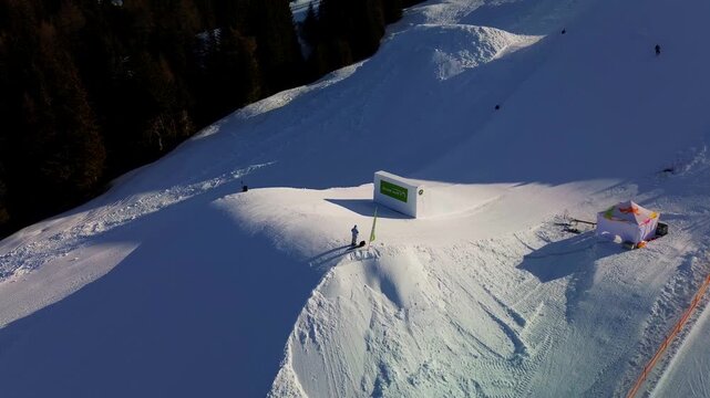 Aerial view of the Seiser Alm snowpark in the heart of the Dolomites. Freestyle ski jumps are set against a backdrop of vast snow-covered plateaus and distant mountain peaks. Aerial view of the profes