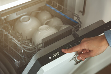 female hand setting cycle on dishwasher
