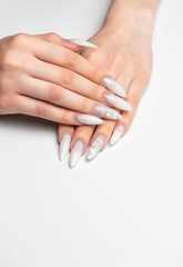 Fototapeta premium Woman hands showing stiletto nail art manicure wearing white glitter