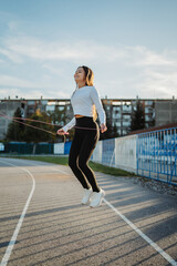 Obraz premium Young woman jumping rope doing fitness workout training