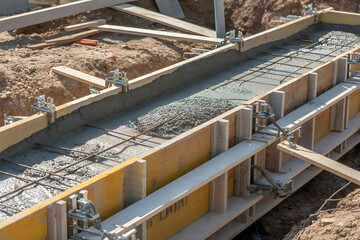 Wet concrete being poured into building foundation formwork