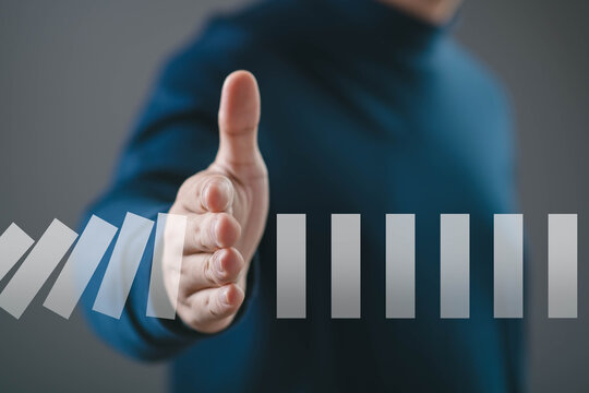 Hand stopping falling domino blocks symbolizing risk control, prevention, stability, and problem management. Concept of crisis prevention, business protection, decision making, strategic intervention.