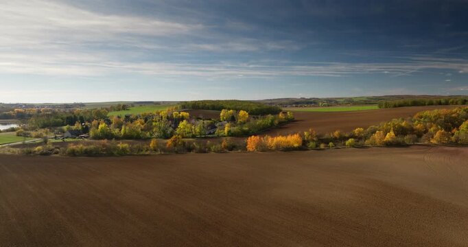 Drone aerial of wide autumn farmland and tree lines in Czech Tuscany near Moravsky Krumlov, Czech Republic.