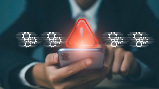 Red warning alert with exclamation mark appears. Smartphone, surrounded gear icons, symbolizing system error, technical issue, process failure, risk detection solutions in digital operations.