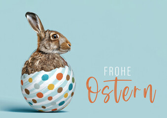 Frohe Ostern Konzept, Ferien Feiertag Gru&szlig;karte, Karte mit deutschem Text - Osterhase Feldhase Hase in Osterei, isoliert auf blauem Hintergrund