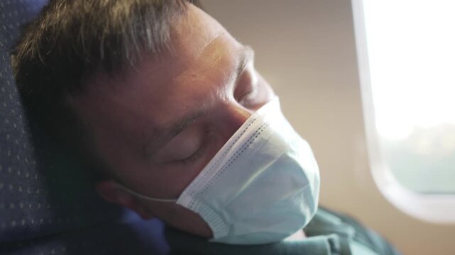 Travel safely public transport. Young man in medical mask sleeps near train window. Train passenger in protective mask on face resting. New normal travel concept. Commuter sleep covid 19, coronavirus.