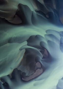 Aerial view of an abstract landscape with dynamic swirls of teal, gray, and lavender, creating a mesmerizing, otherworldly scene, Selfoss, Iceland.