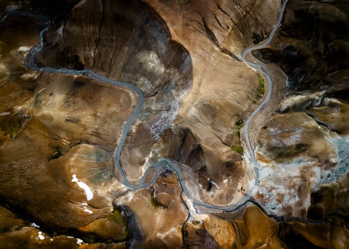 Aerial view of a serpentine river snaking through ochre and ivory terrain, cutting a path through Iceland's rugged beauty, Selfoss, Iceland.