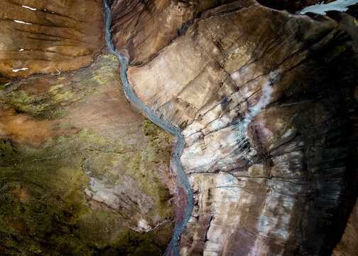 Aerial view of a glacial river carves through the landscape's rich tapestry of ochre and umber hues, creating a mesmerizing dance of light and shadow, Selfoss, Iceland.