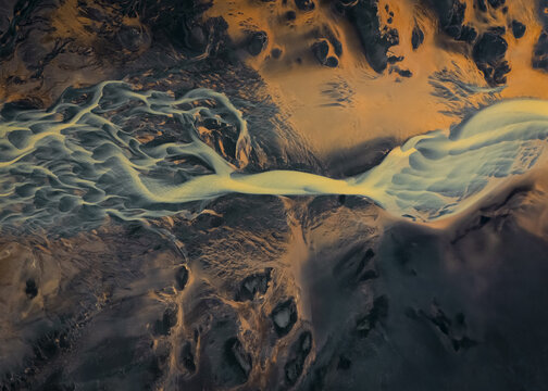 Aerial view of braided rivers carving through the volcanic landscape, creating intricate patterns with contrasting colors and textures, Selfoss, Sveitarfelagid Arborg, Iceland.