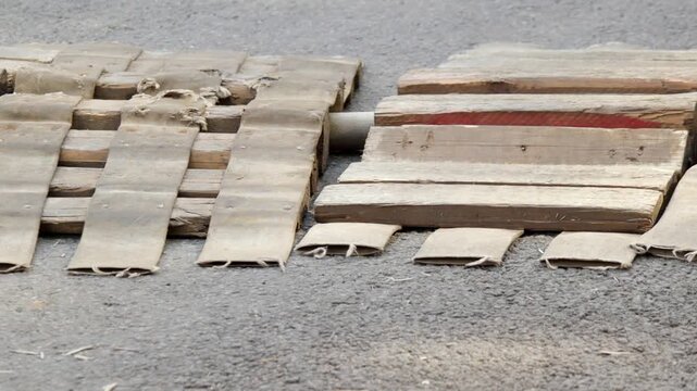 Wooden plank crossing placed over flexible industrial hose on asphalt surface. Setup allows vehicles to pass without damaging hose.