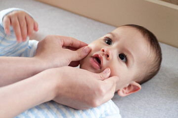 Happy Baby boy lying, mother's hand pressing her cheeks