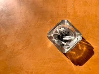 The cigarette butt was on the glass tray placed on the wooden table.