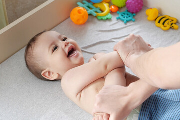 Mother doing massage on her healthy infant baby. Caring Woman Making Gymnastics To little Baby