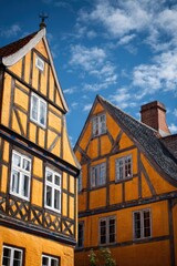 Fototapeta premium Colorful houses stand in a historic area showing timber framing and vibrant paint against a blue sky with clouds in a small town in Europe
