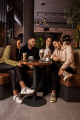 Fototapeta na wymiar Group of friends sitting at a bar table in a café and having fun