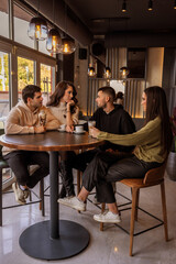 Group of friends sitting at a bar table in a café and having fun