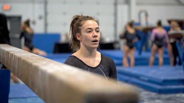 Young gymnast demonstrating persistence and struggle on the balance beam in a gymnastics training facility