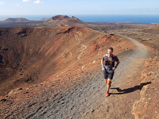 An athletic middle-aged man runs along the island's mountainous volcanic trail.