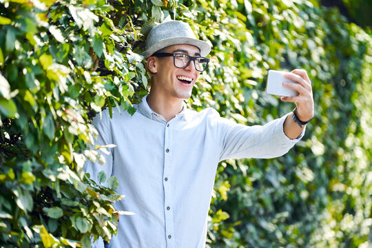 Happy young man taking selfie in a hedge