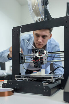 Student setting up 3D printer, using laptop