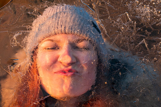 Portrait of teenage girl pulling funny face behind ice-covered surface
