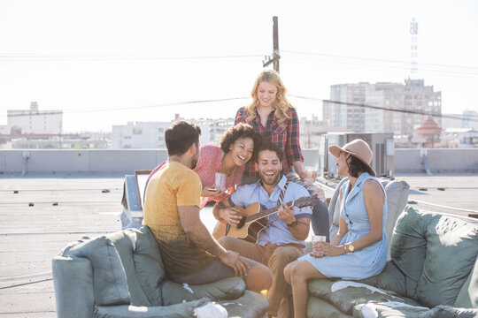 Friends having a rooftop party and playing guitar