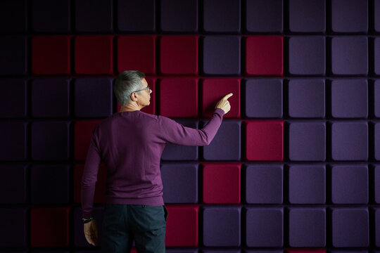 Businessman touching noise reduction wall in office