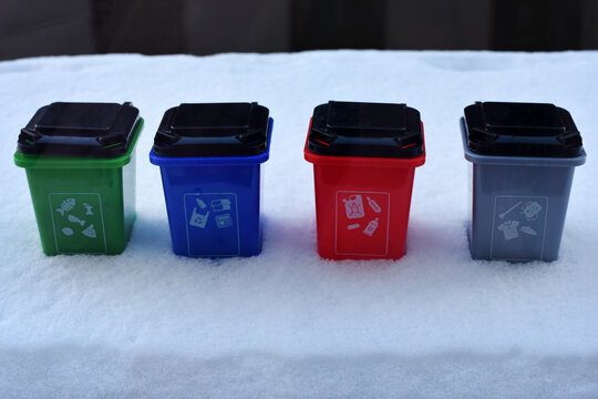 Colorful recycling toy boxes standing in snow, plastic classification trash cans as children's educational toys. Ecology and next generation concept