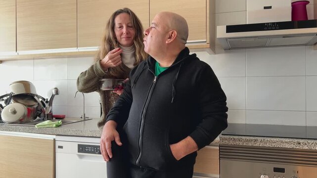 Pareja relajada compartiendo un bol de frutas en la cocina