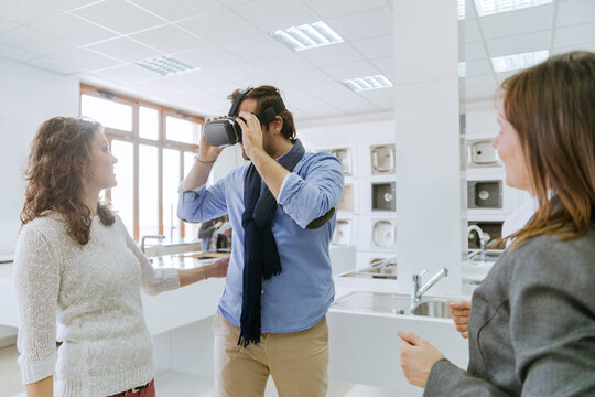 Customers consulting saleswoman in shop for kitchen sinks