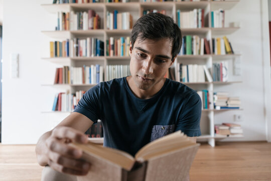 Young man reading book at home