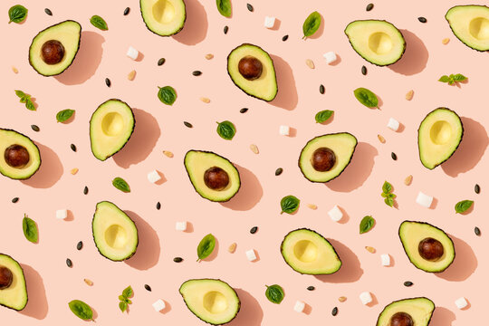 Pattern of halved avocados, pumpkin seeds, basil and pieces of cheese