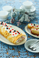 Homemade pancake roll called Finnish pancake with cream cheese and berry confit on table with blue lace tablecloth