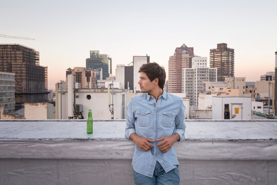 Confident young man standing on a rooftop terrace