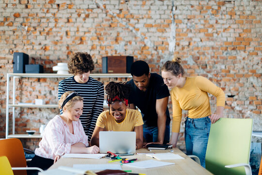 Young people working together at table using laptop