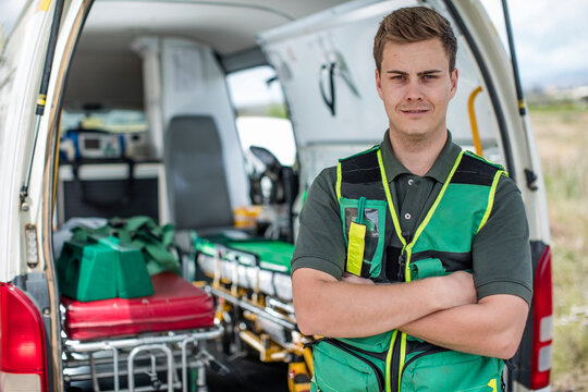 Paramedic standing with arms crossed in front of ambulance