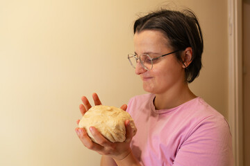 Woman holding dough in kitchen with contented expression