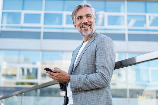 Smiling mature businessman with cell phone outdoors